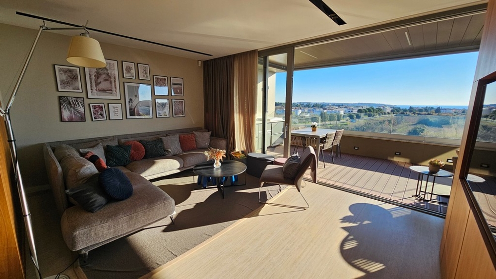 Obývacia izba s veľkým preskleným priečelím a výhľadom na more