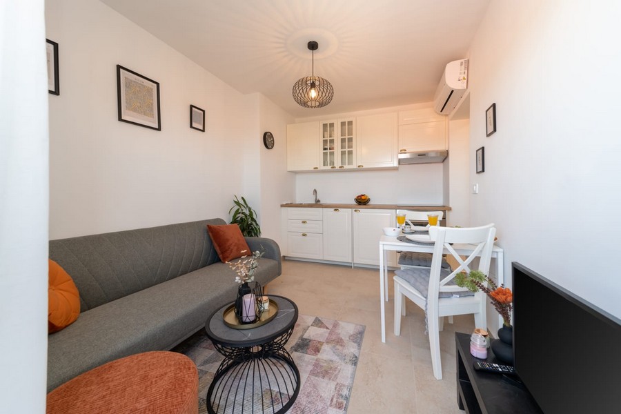 Obývacia izba s pohovkou, stolom a otvorenou kuchyňou