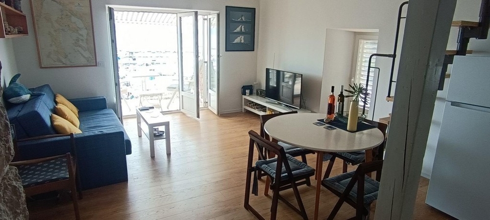 Obývacia izba s pohovkou, jedálenským stolom a prístupom na balkón s výhľadom na more
