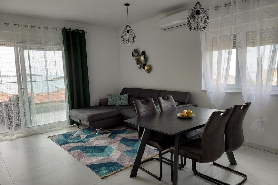 Obývacia izba s pohovkou, jedálenským stolom a výhľadom na more cez veľké okno