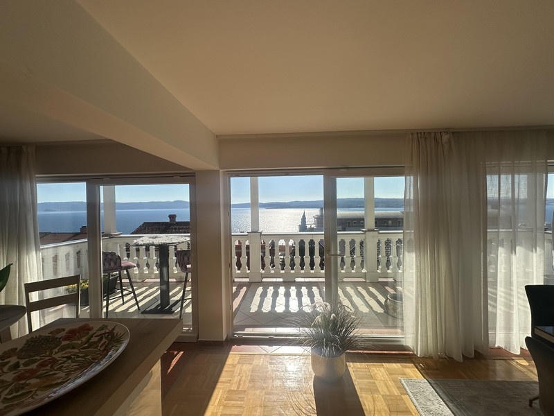 Obývacia izba s veľkým oknom a prístupom na balkón s výhľadom na more