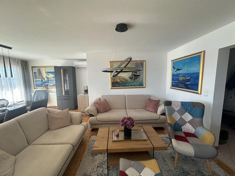 Svetlá obývacia izba s pohovkou, konferenčným stolíkom a nástennými obrazmi