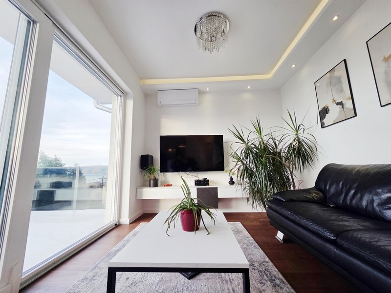 Obývacia izba s veľkým preskleným priečelím a prístupom na terasu s výhľadom na more