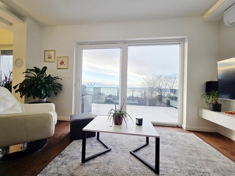 Svetlý obývací priestor s posuvnými dverami a výhľadom na mesto a more