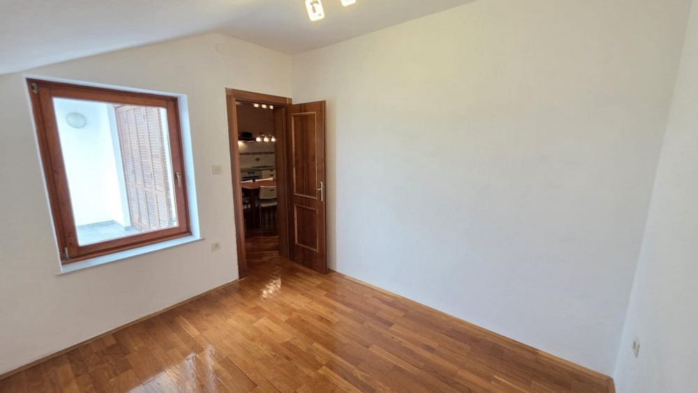 Spálňa s drevenou podlahou a oknom