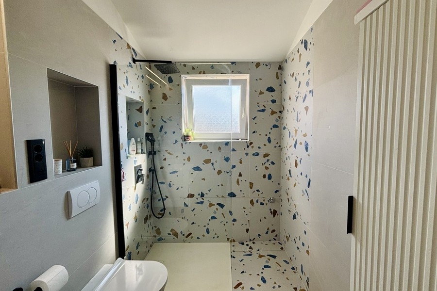 Moderná kúpeľňa so sprchovacím kútom na úrovni podlahy a oknom