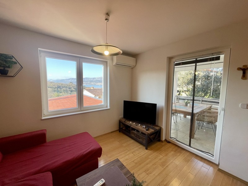 Obývacia izba s pohovkou, TV a balkónom s výhľadom na more