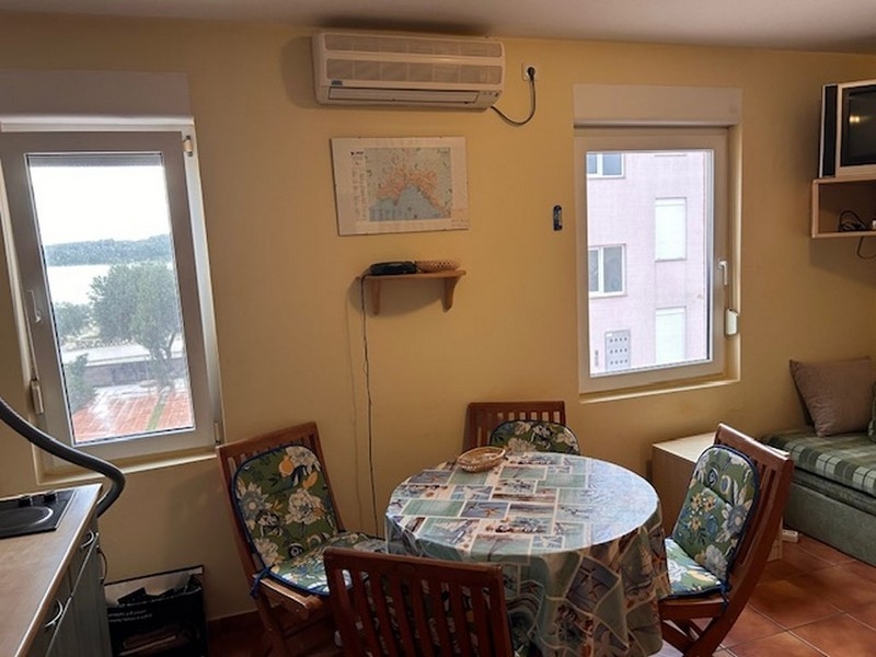 Obývacia izba a jedálenský kút s okrúhlym stolom a výhľadom na more cez okno