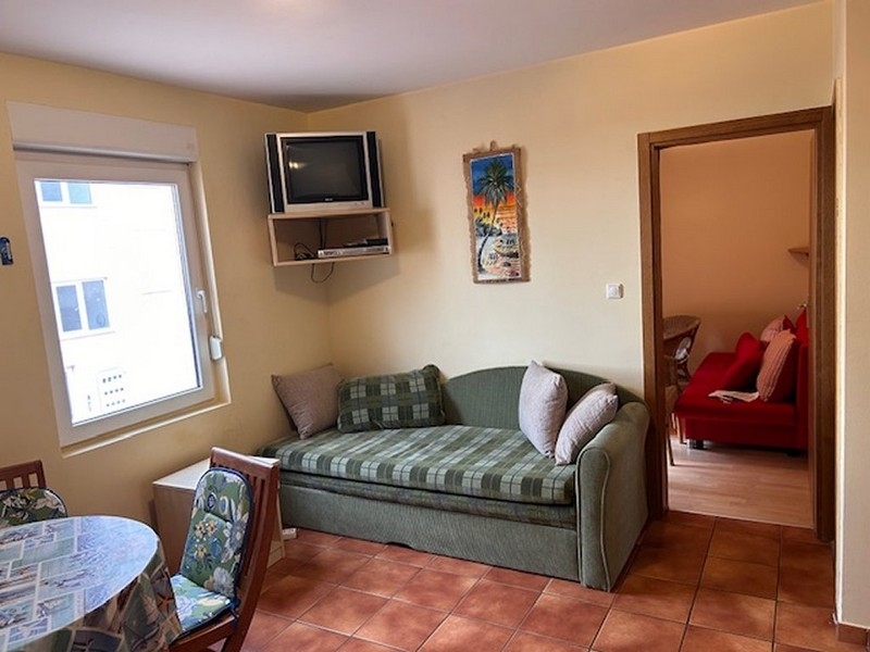 Kompaktná obývacia izba s pohovkou, TV a vstupom do spálne