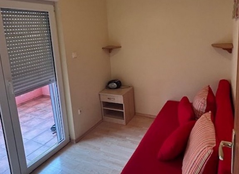 Spálňa s červenou pohovkou a prístupom na balkón