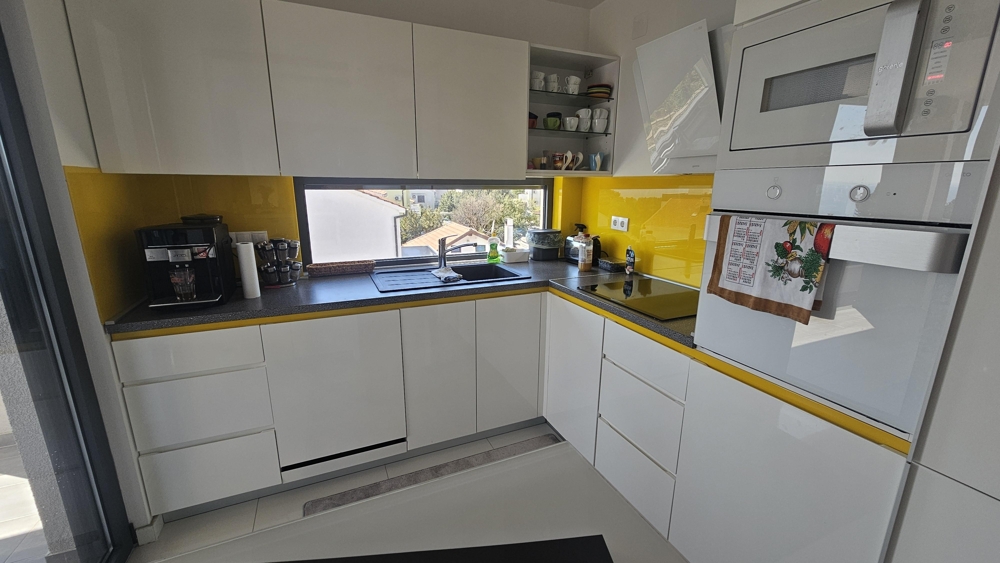 Moderná kuchynská linka so vstavanými spotrebičmi a oknom