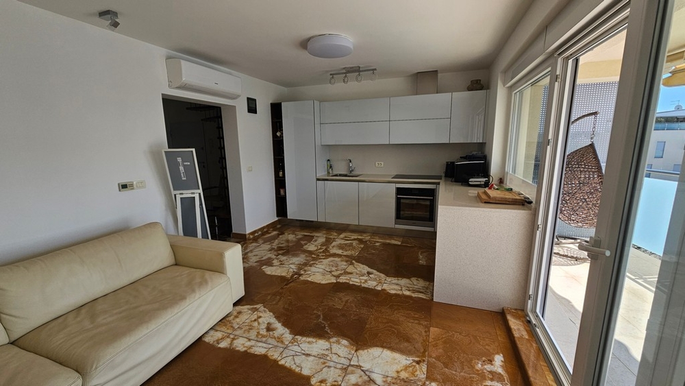 Otvorená obývacia izba s moderne vybavenou kuchyňou a vstupom na terasu