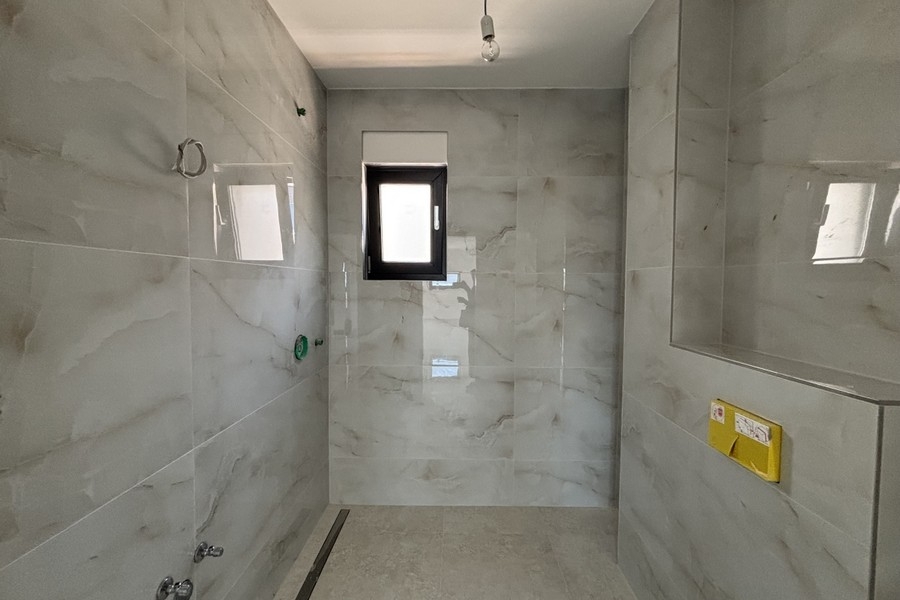 Moderná kúpeľňa so sprchovacím kútom na úrovni podlahy a oknom
