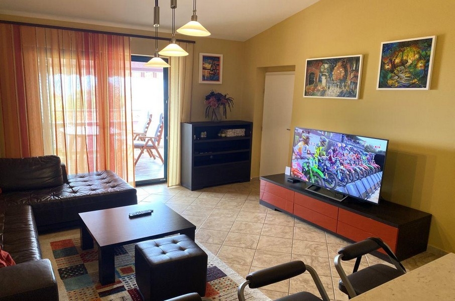 Obývacia izba s pohovkou a prístupom na balkón v rekreačnom apartmáne na Krku