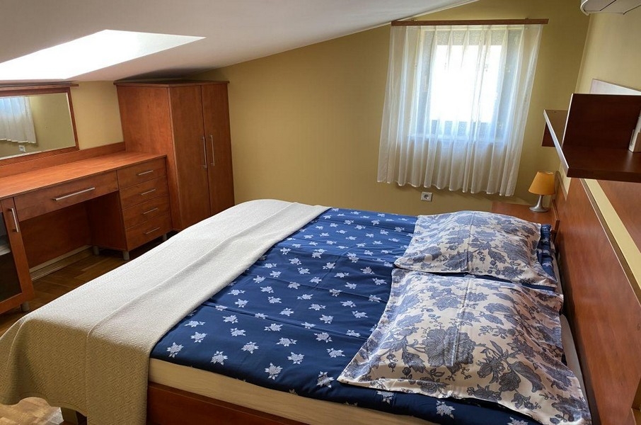 Spálňa s manželskou posteľou a strešným oknom v apartmáne na Krku