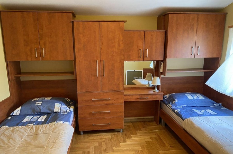 Spálňa s jednolôžkami a dreveným nábytkom v rekreačnom apartmáne