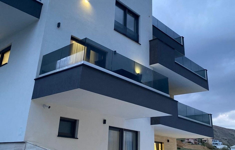 Moderná obytná budova s ​​balkónmi a skleneným zábradlím na Pagu
