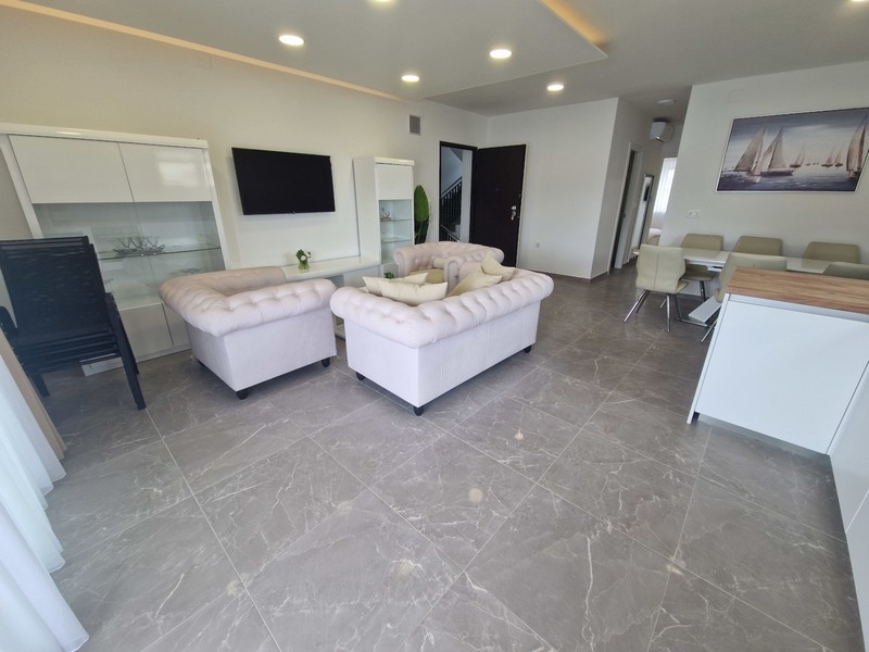 Otvorený obývací priestor s kuchyňou a výhľadom na more v modernom apartmáne