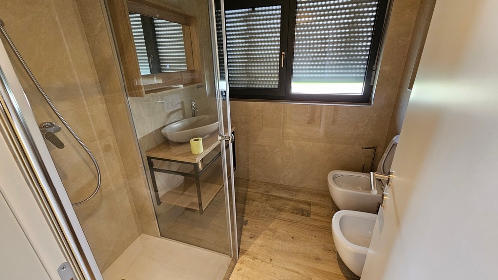 Moderná kúpeľňa so sprchovacím kútom a oknom