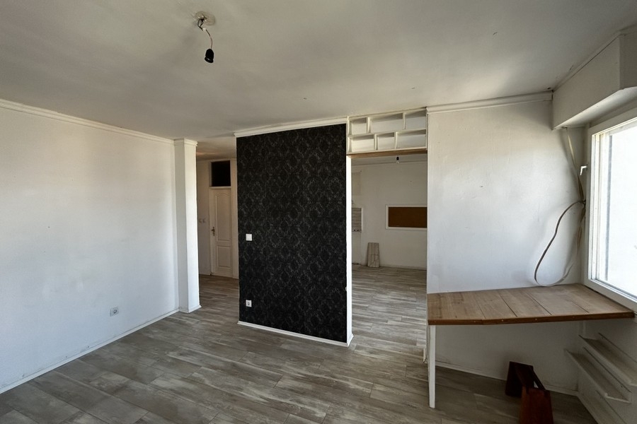 Obývacia časť s laminátovou podlahou a oknom od podlahy až po strop