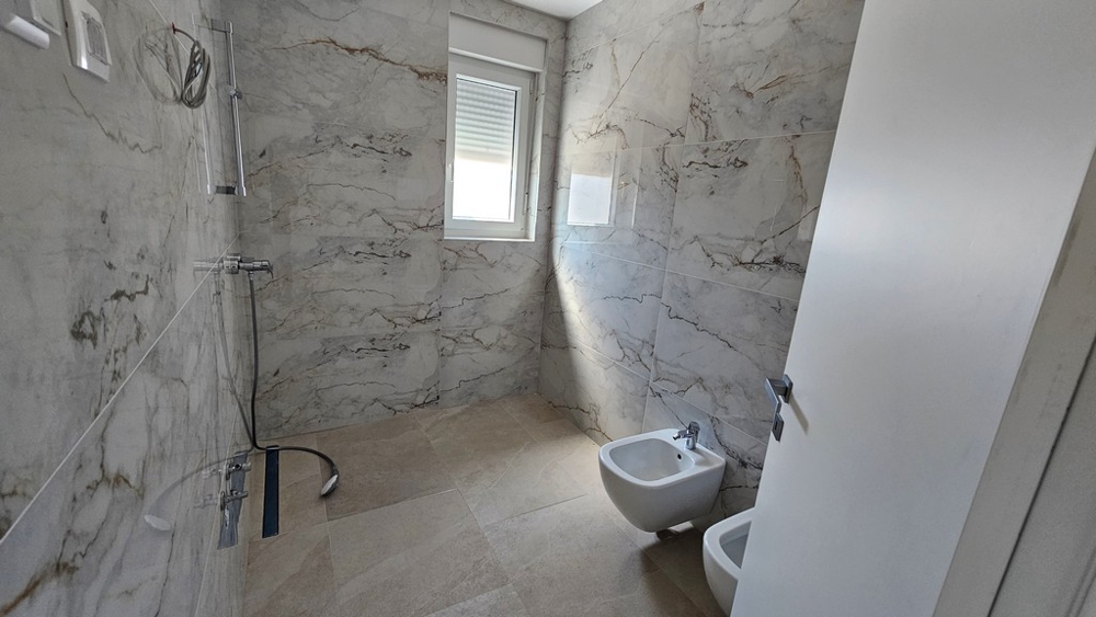 Moderná kúpeľňa so sprchovacím kútom a mramorovým vzhľadom