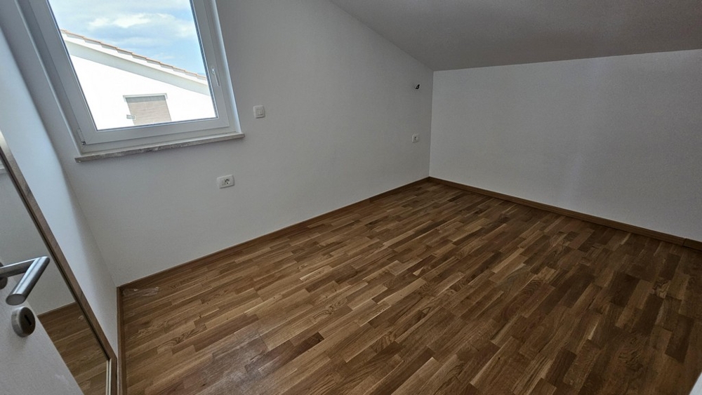 Spálňa so strešným oknom a parketovou podlahou