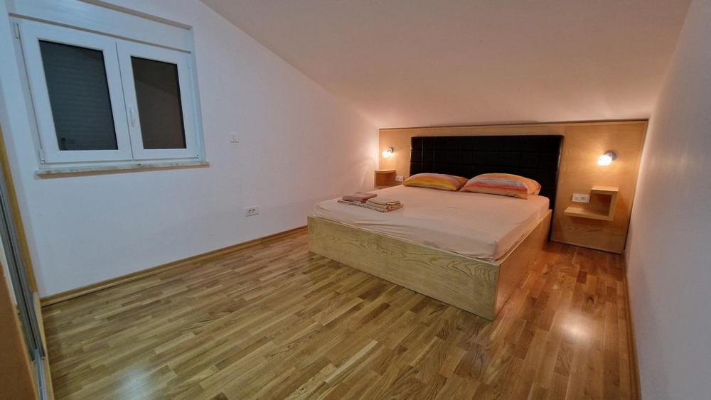 Spálňa s manželskou posteľou a drevenou podlahou v Njivice na Krku