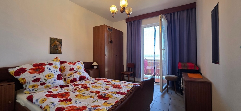 Spálňa s manželskou posteľou a balkónovými dverami, apartmán A4103