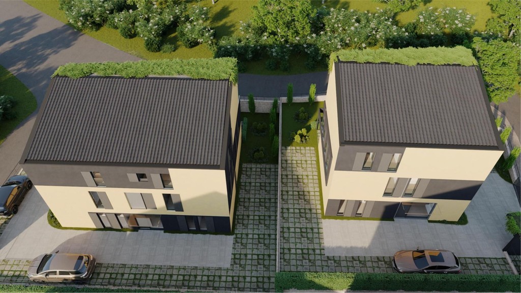 Letecký záber dvoch budov so zelenými strechami a parkovacími miestami