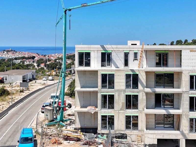 Hrubá stavba s žeriavom, za ňou staré mesto pri mori