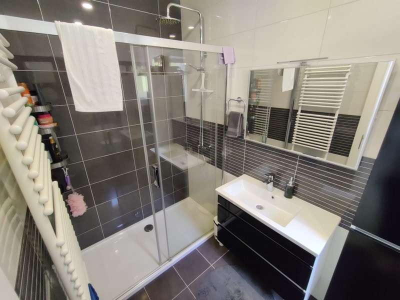 Kúpeľňa s hnedými obkladmi a sprchovacím kútom.