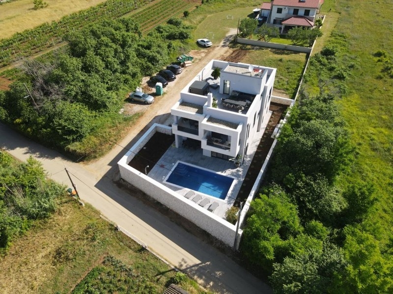 Letecký pohľad na modernú vilu s bazénom a strešnou terasou