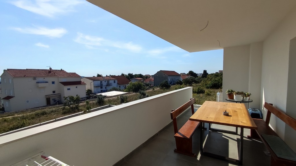 Priestranný balkón s jedálenským kútom rodinného domu vo Vodiciach v Chorvátsku s výhľadom na tiché okolie.