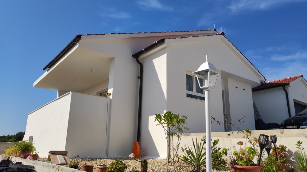 Bočný pohľad na dom na predaj vo Vodiciach, Chorvátsko, s bielou fasádou a terasou.