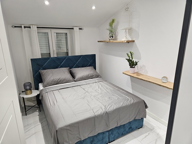 Útulná spálňa s modrým čelom a ozdobnými rastlinami v nehnuteľnosti v Chorvátsku