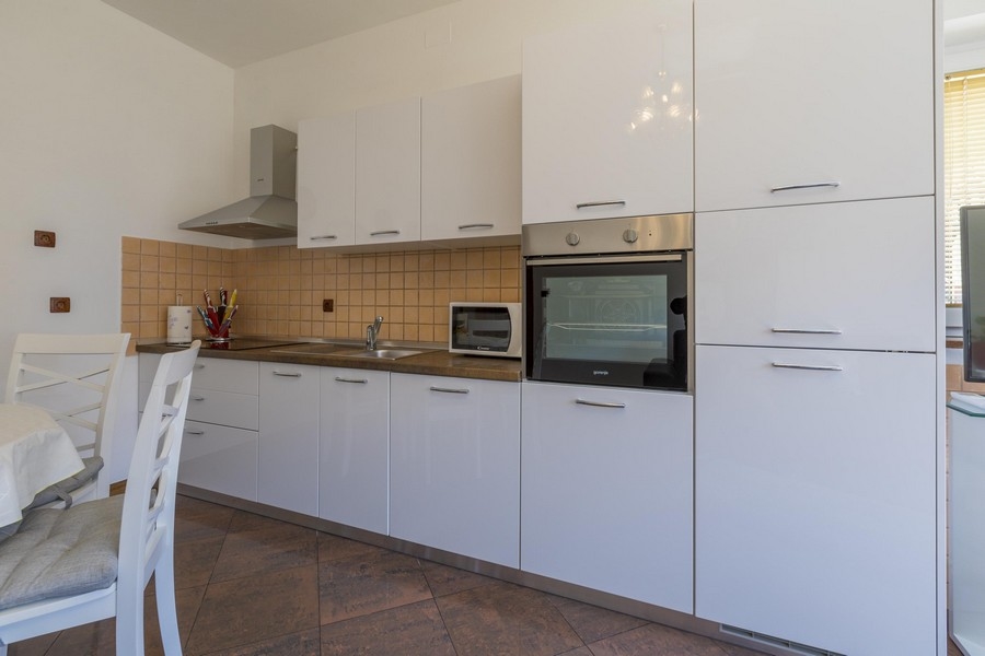 Moderná biela kuchyňa s jedálenským kútom v prímorskej nehnuteľnosti v Chorvátsku