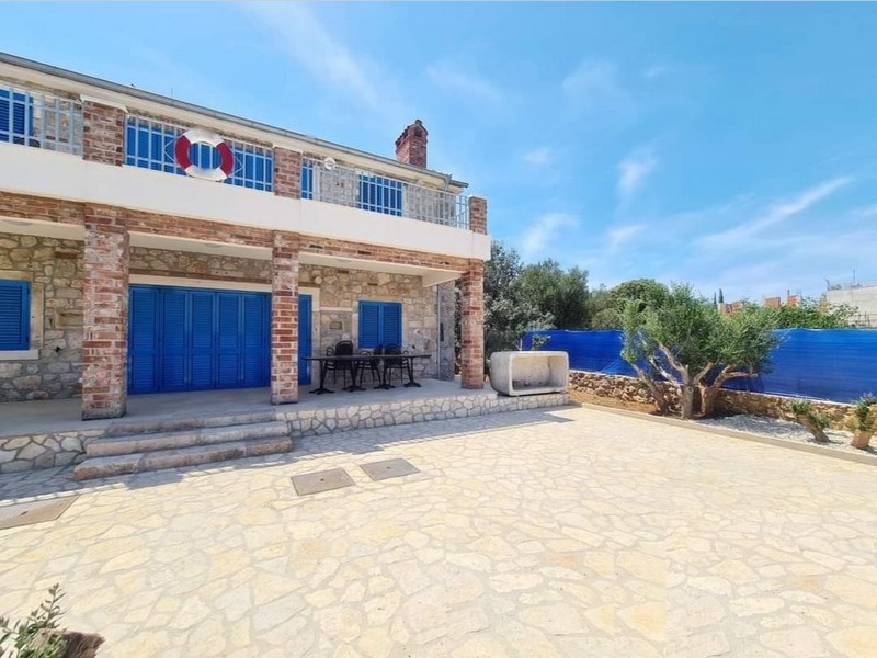 Pohľad spredu na očarujúci kamenný dom na predaj v Chorvátsku s vonkajším jedálenským kútom.