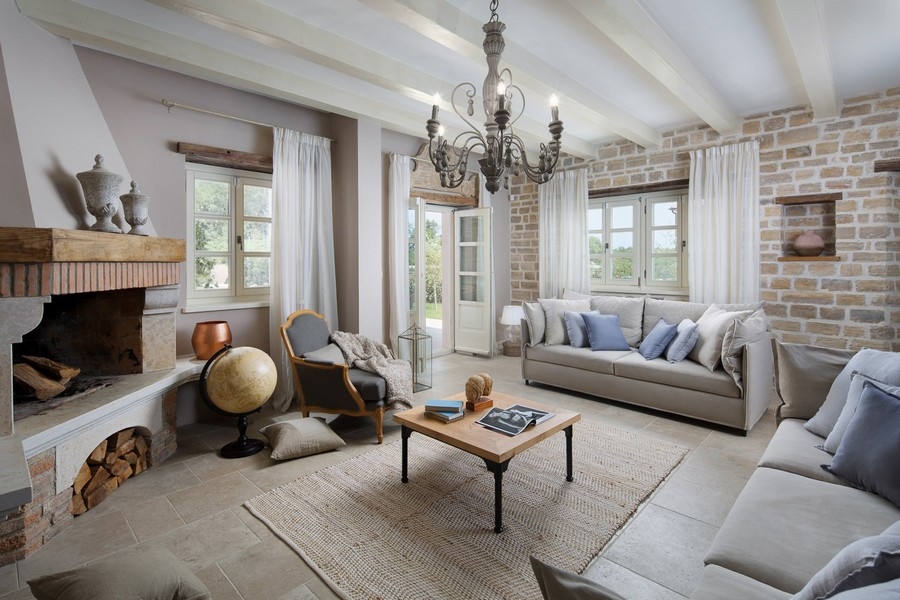 Útulná obývacia izba s krbom, pohodlnými pohovkami a prirodzeným svetlom prenikajúcim cez závesy - Real Estate Croatia