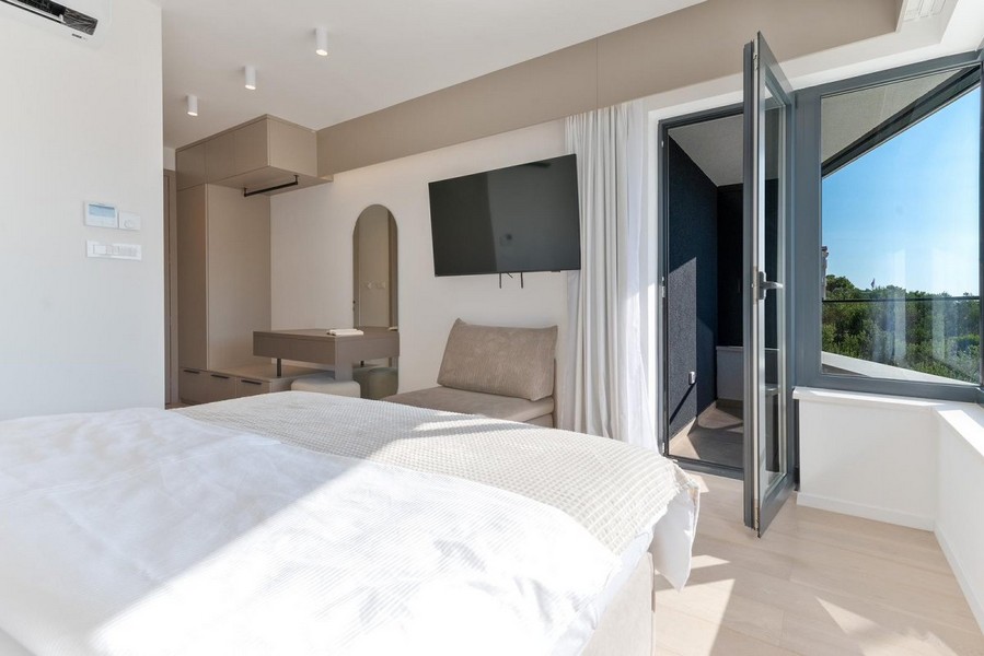 Spálňa v chorvátskej vile na predaj s moderným dizajnom a prístupom na balkón.