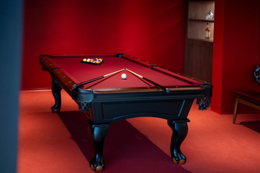 Biliardová miestnosť vo vile v Chorvátsku na predaj s červenými stenami a luxusným biliardovým stolom.
