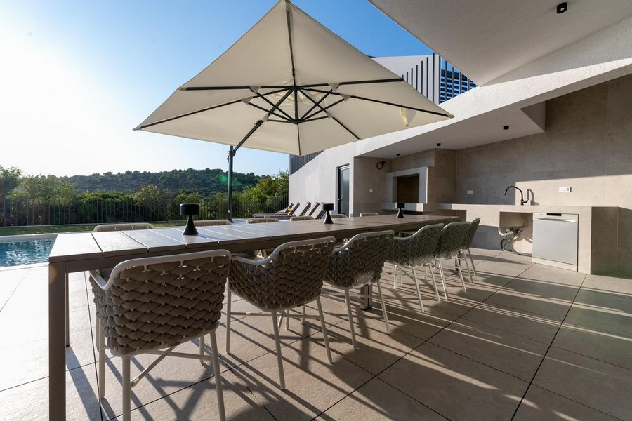 Elegantná vonkajšia terasa vily v Chorvátsku s jedálenským stolom a kuchyňou.