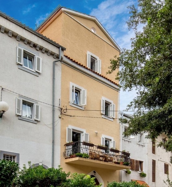 Fasáda žltého domu ako súčasť nehnuteľnosti v Chorvátsku s balkónmi a žalúziami