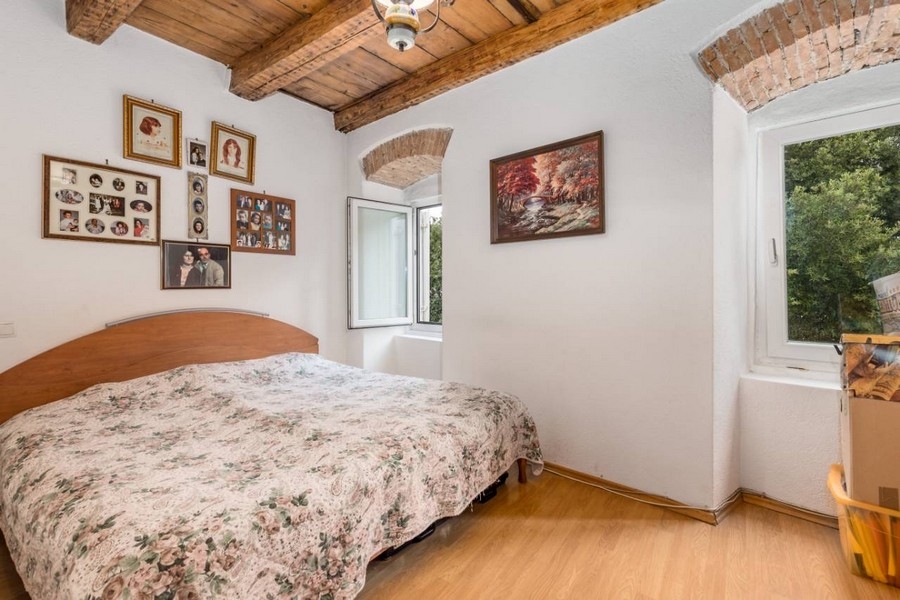 Spálňa nehnuteľnosti v Chorvátsku s manželskou posteľou a odhalenými trámami