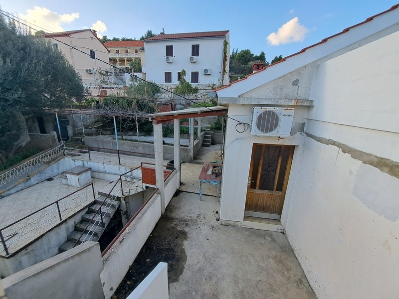 Zadný dvor chorvátskeho pozemku s krytou terasou a schodiskom, ktorý ponúka na predaj Panorama Scouting.