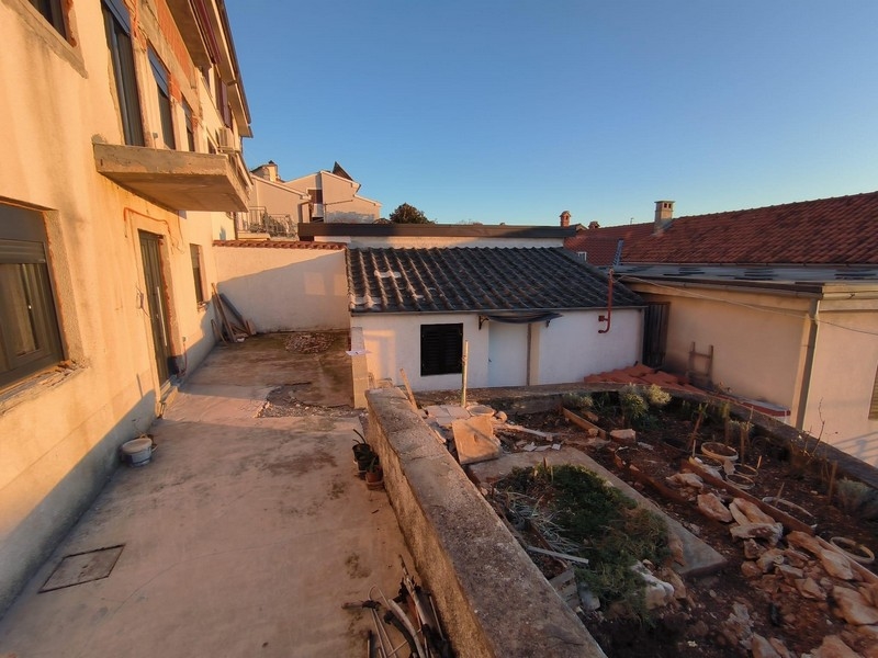 Zadná časť nehnuteľnosti v Chorvátsku s výhľadom na susedné budovy a záhradu