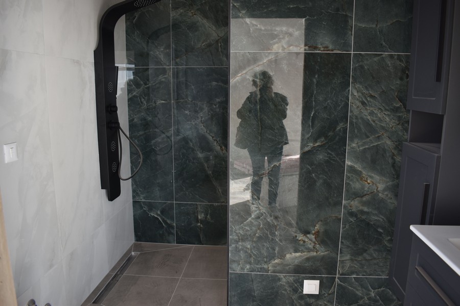 Elegantný sprchový kút s tmavými mramorovými obkladmi vo vile na predaj na ostrove Krk v Chorvátsku.