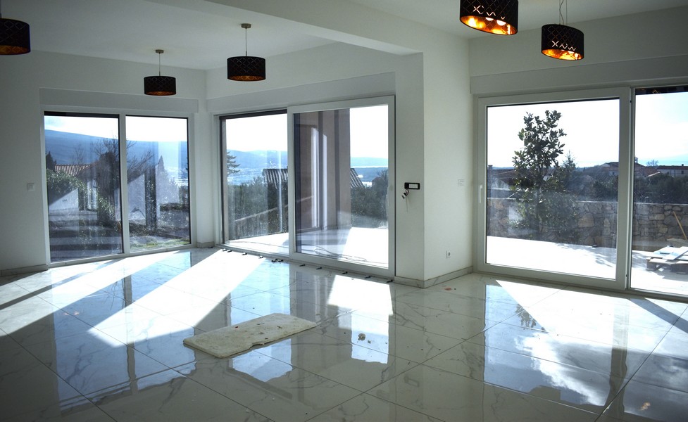 Svetlá, slnkom presvetlená obývacia izba vo vile na Krku s veľkými oknami a výhľadom na more.