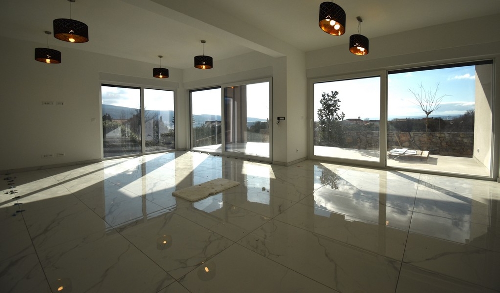 Odraz slnečného svetla na lesklej podlahe obývačky vo vile na Krku.