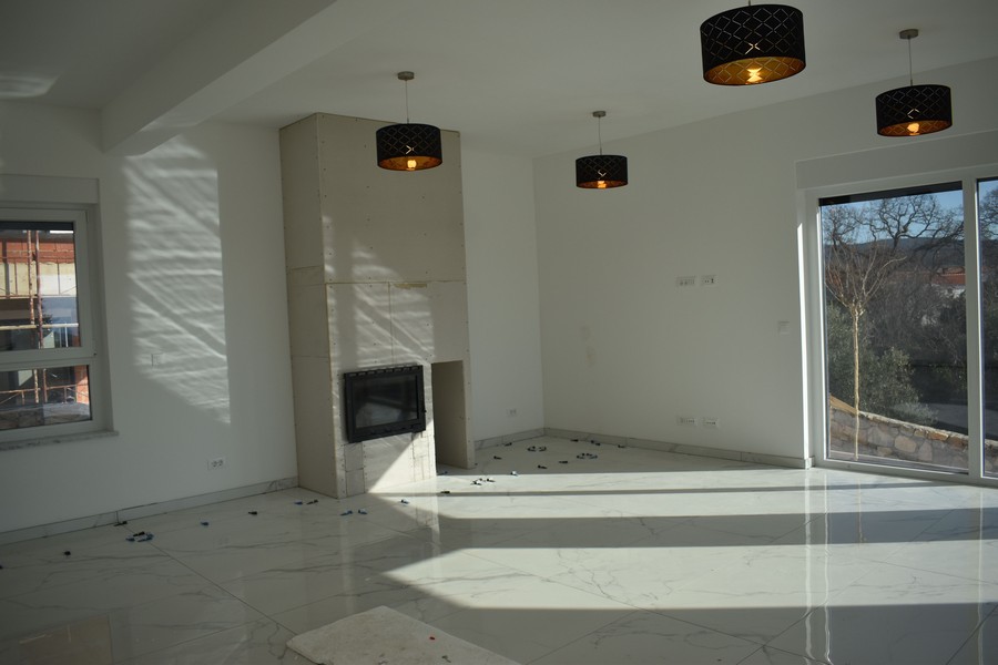 Pohľad do interiéru obývačky s krbom a výhľadom do prírody vo vile na Krku.