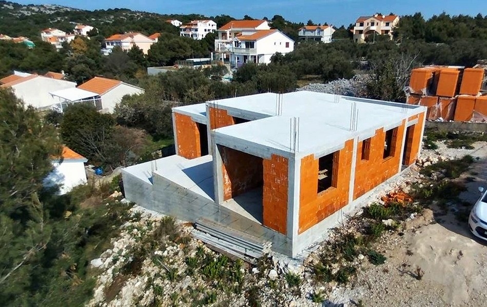 Detailný pohľad na stavbu vily s odhalenými tehlovými stenami a betónovými stĺpmi na predaj na ostrove Krk v Chorvátsku